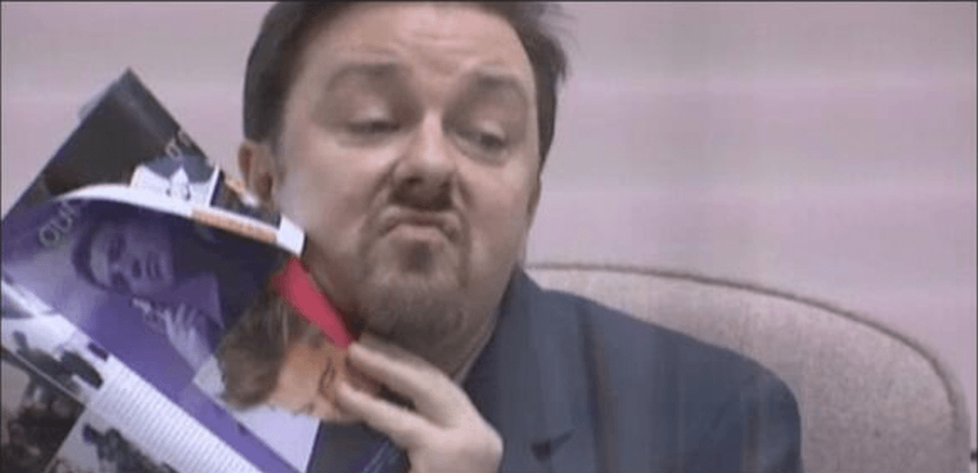 David Brent from The Office wiping a magazine page on his face